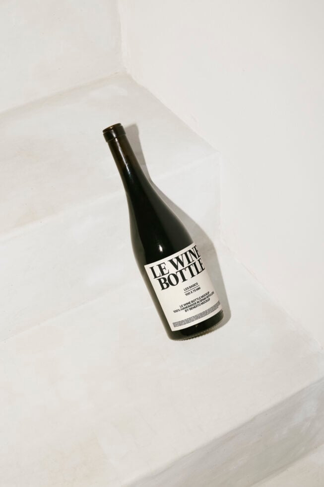Dark wine bottle labeled Le Wine Bottle on white steps background minimalist photography perfect for mockups branding design templates typographySEO