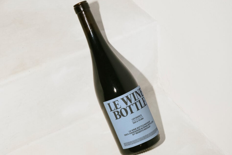 Dark wine bottle mockup tilted on white background, overhead product photography view