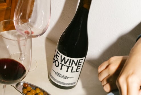 Wine bottle mockup on a table with glasses and olives. Perfect for designers seeking realistic product mockups. Keywords: mockup, design, template, wine.