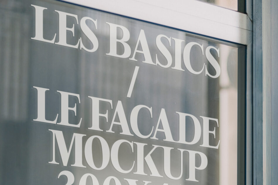 Close up of store window with light serif type Les Basics facade mockup lettering