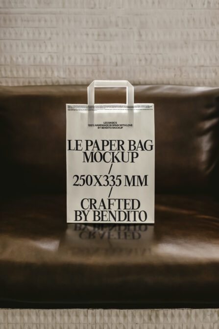 Off white craft paper bag mockup with handles resting on brown leather chair