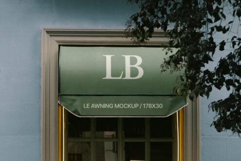 Green awning mockup template on a window with foliage. Perfect for designers needing realistic storefront graphics or architecture-themed designs.