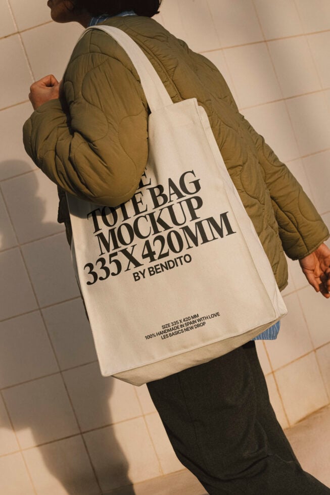 Mockup of a tote bag 335x420mm carried by a person in a beige jacket. Ideal for showcasing design templates and branding. High-quality fabric texture.