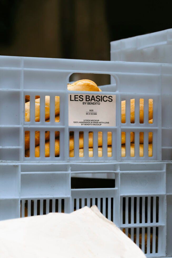 Plastic crate with label Les Basics by Bendito. Bread inside. Mockup for packaging design, handmade product showcasing. Ideal for templates or graphics.