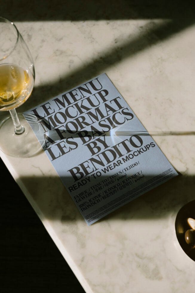 Elegant menu mockup on marble surface beside a glass of white wine. Perfect for designers seeking chic and realistic presentation templates.
