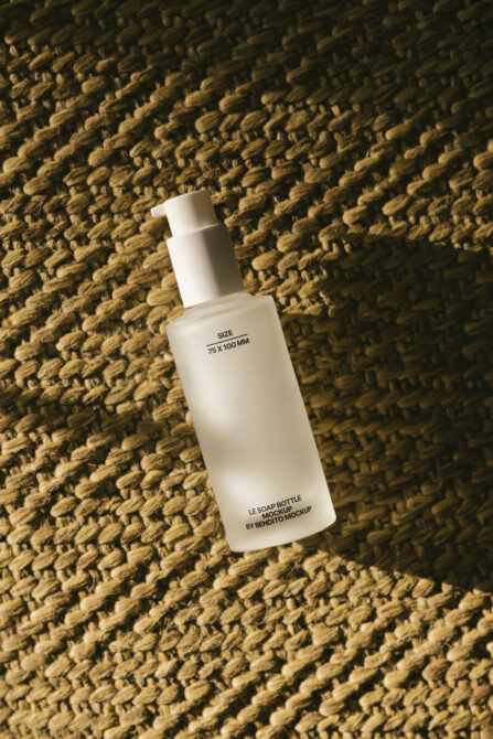 White soap bottle mockup on textured gold fabric with sunlight