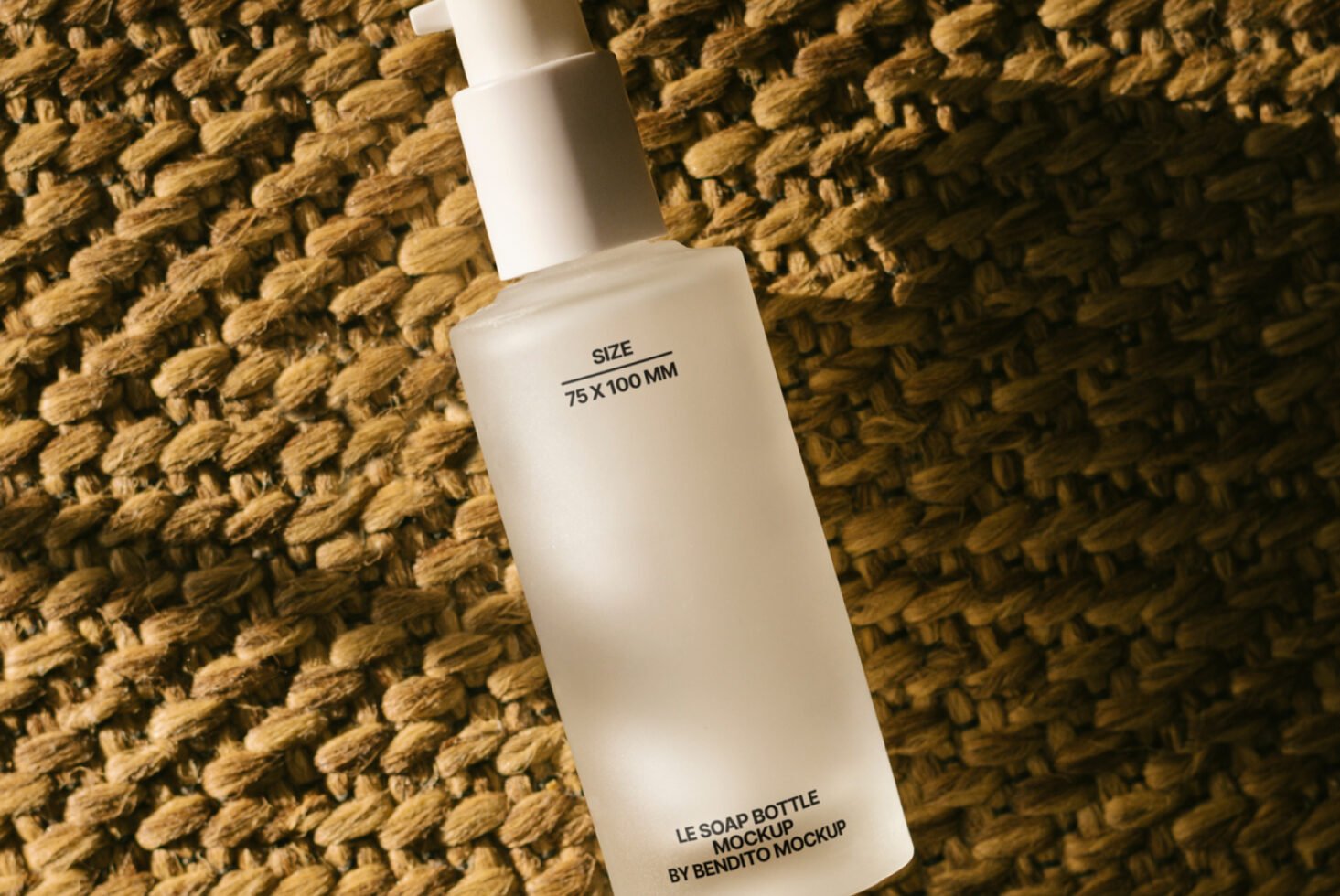 Frosted soap bottle mockup with pump, placed on textured woven surface, ideal for showcasing skincare product designs and packaging concepts for designers.