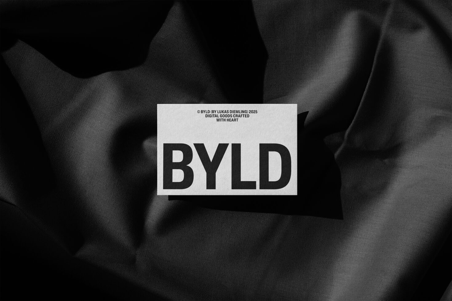 Minimalist mockup featuring BYLD text on a card over textured black fabric suitable for branding or digital asset presentation for designers.