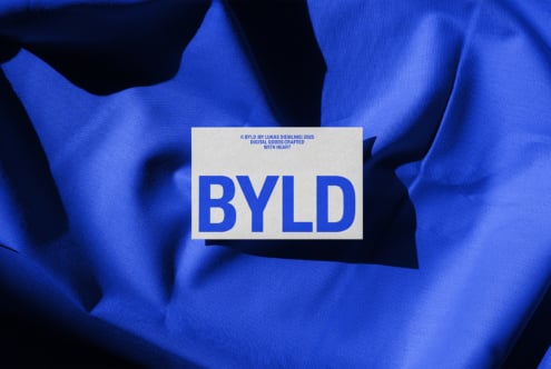 BYLD logo on white card over crumpled blue fabric with bright shadows