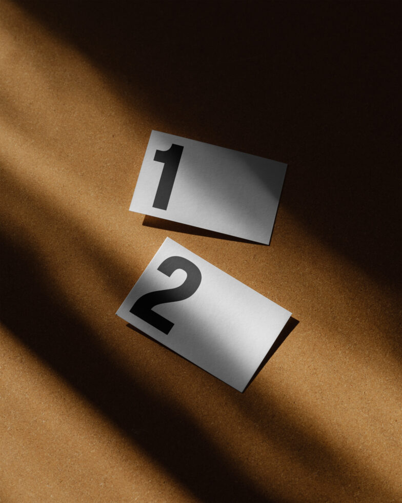 Minimalist mockup featuring two numbered cards on a brown textured surface with dramatic lighting, perfect for modern graphic design projects and templates.