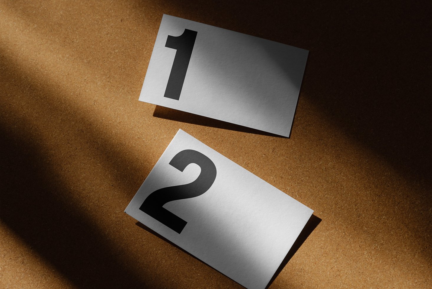 Minimalist business card mockup on cork background featuring bold numbers 1 and 2 with dramatic lighting ideal for graphic designers and branding projects