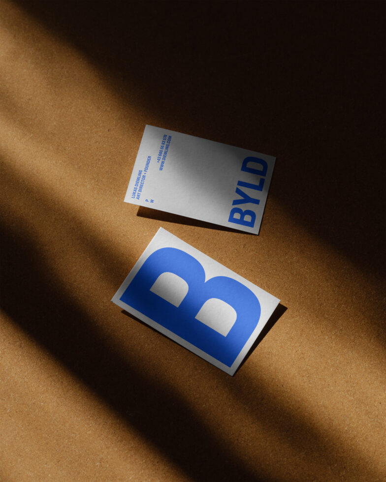 Business card mockup featuring minimalist design with bold blue typography byld on brown textured background ideal for designers showcasing templates