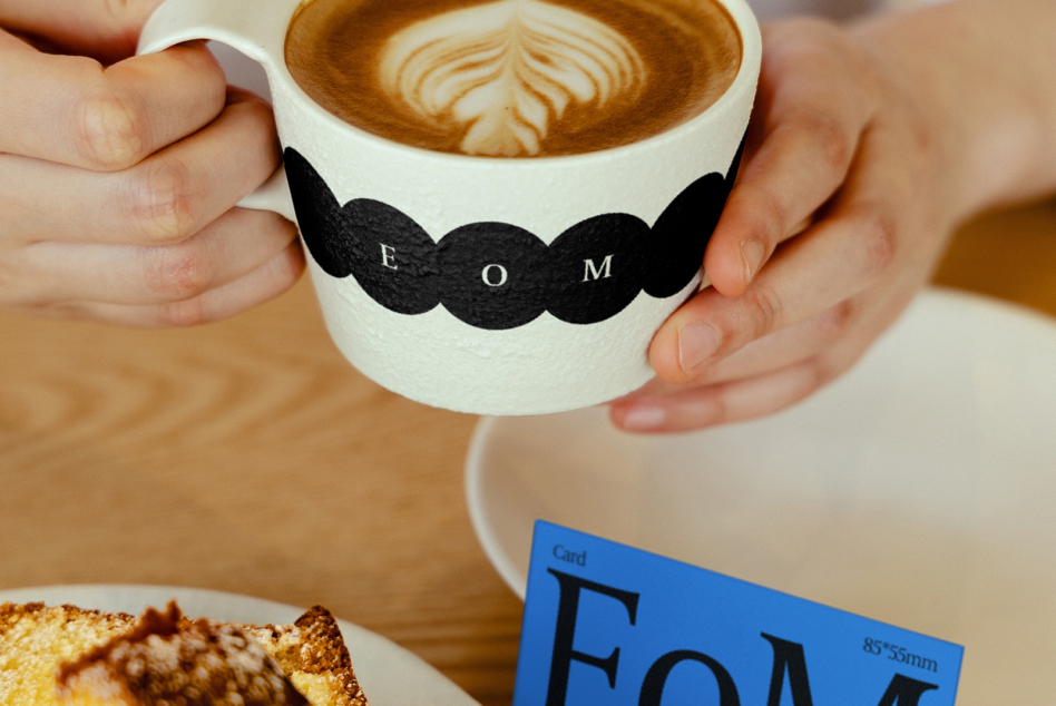 White mug with black wavy stripe design held with blue card below