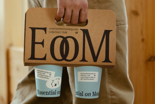 Brown kraft paper coffee carrier with large EoM letters displayed by person