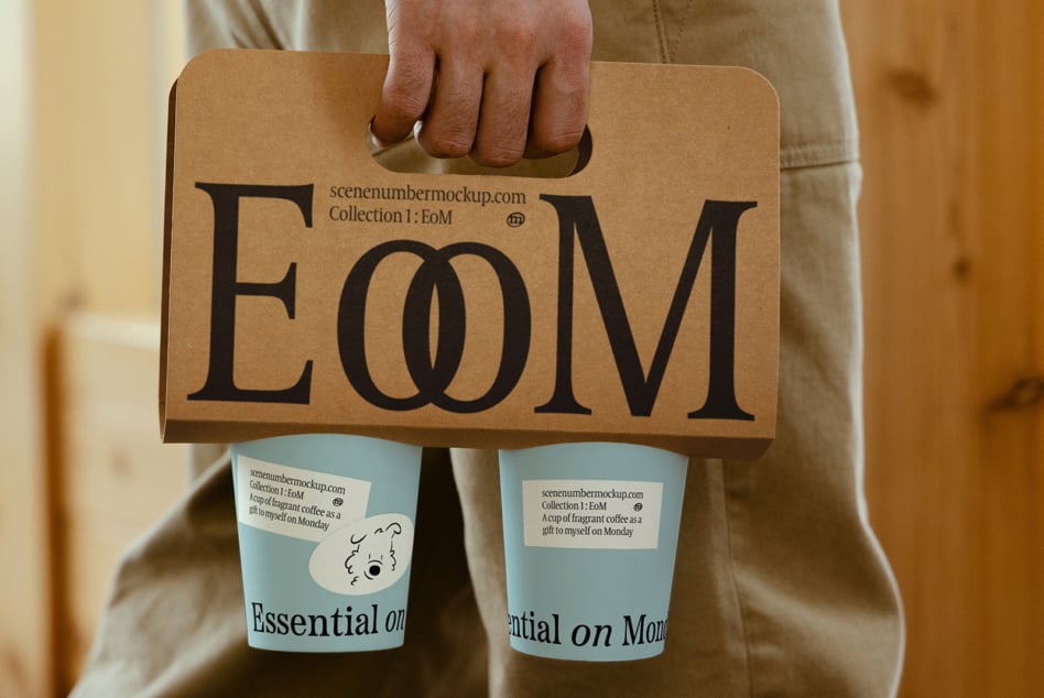 Brown kraft paper coffee carrier with large EoM letters displayed by person