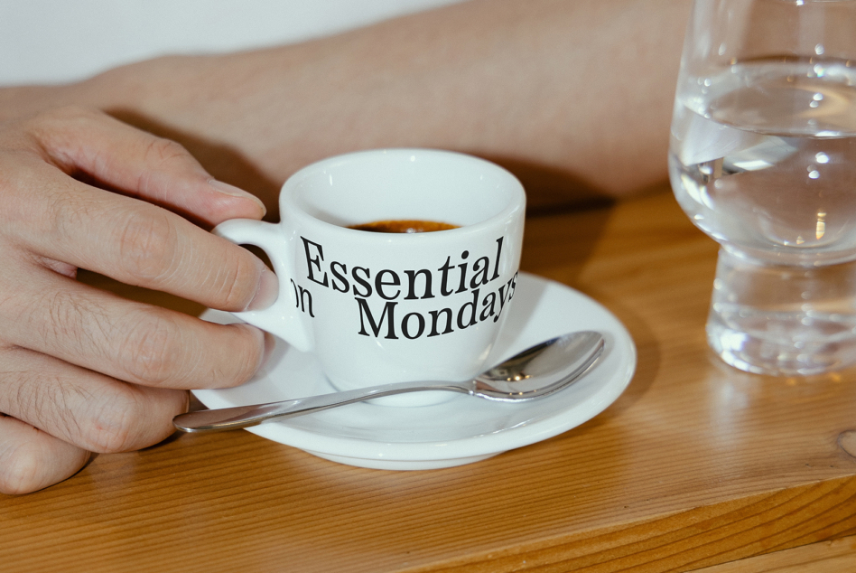 Black text on white espresso cup with Essential on Mondays phrase