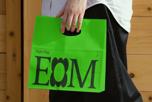 Green paper bag mockup in hand, showcasing modern design and typography. Ideal for branding, graphic design, digital assets, designers resources.