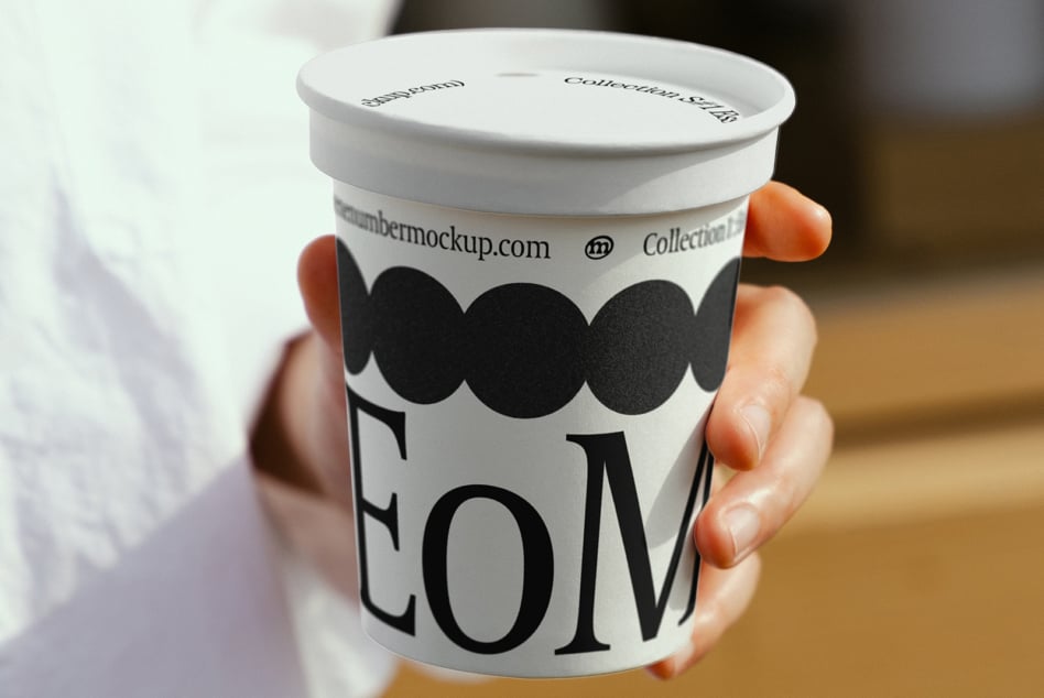 White paper cup with lid in hands showing circular pattern design