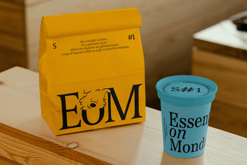 Golden yellow paper bag with EOM logo next to turquoise coffee cup
