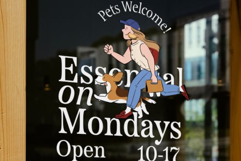 Storefront window sign with design illustration of woman and dog. Text reads Pets Welcome Open Mondays. Ideal for graphics and branding mockups.