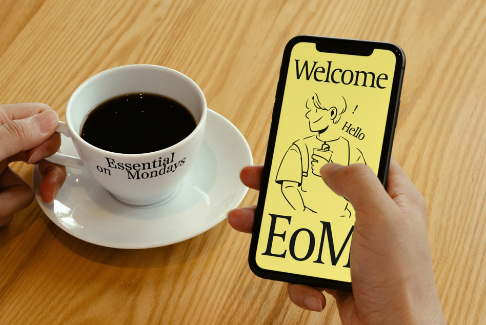 Yellow phone screen mockup with welcome illustration next to white coffee cup on wood