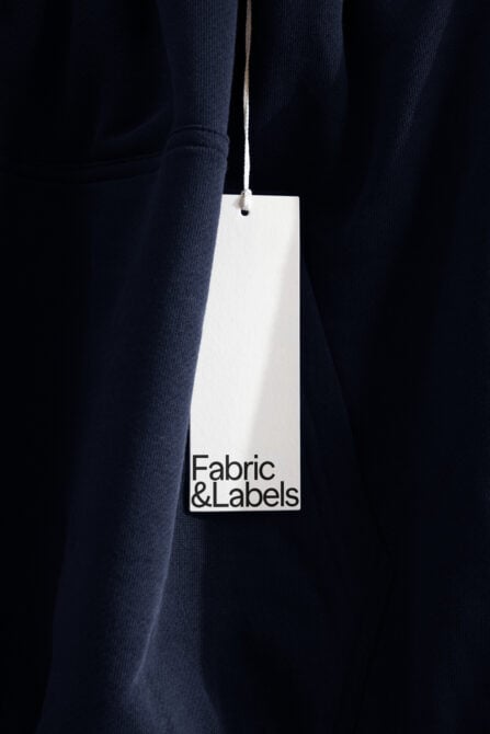Hanging white clothing tag on navy fabric with twine rope