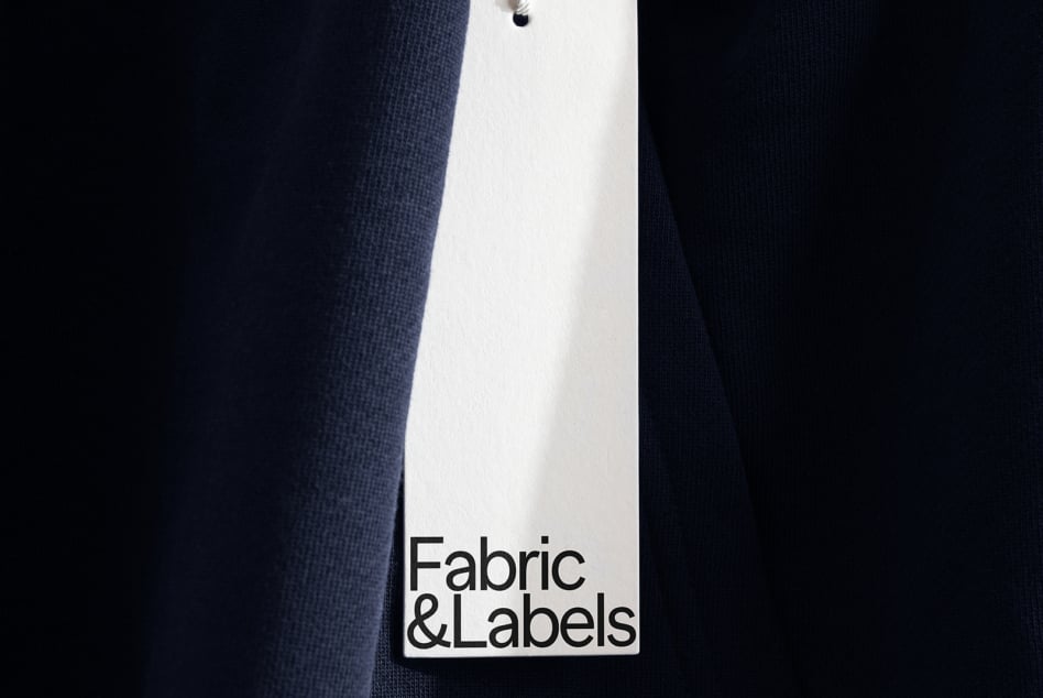 White product label hanging from dark navy textured garment