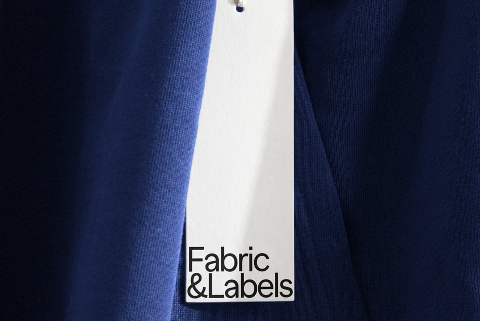 Blank white rectangular clothing tag attached to dark blue fabric