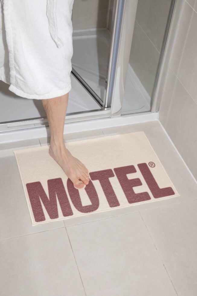 Person stepping onto motel bath mat from shower in bathroom setting mockup mat design typography home decor bath essentials designers asset