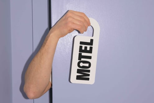 Hand holding a motel door hanger against a purple background perfect for mockup designs promotional graphics designers templates resources signage