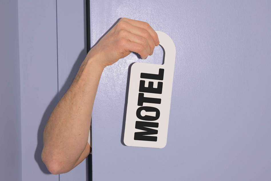 Door hanger tag reading motel on purple wall background