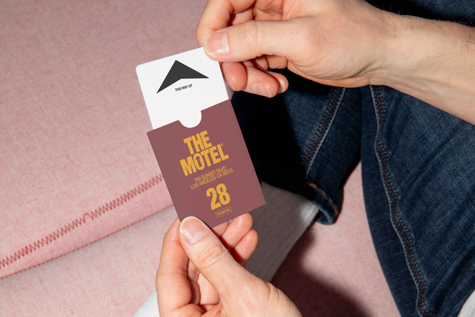 Hands displaying burgundy motel key tag with gold text