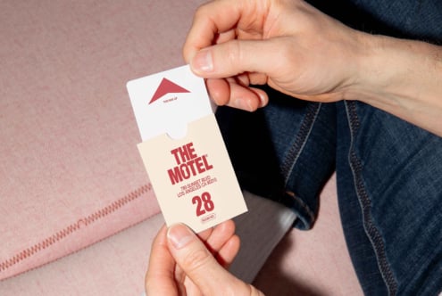 Hands holding a motel key card and room cardholder with bold font design. Ideal for branding, graphics, and mockup use. Design asset for creatives.
