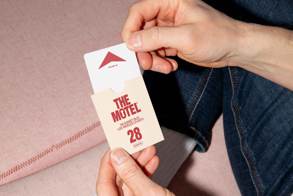 Hands holding cream colored motel key tag with red lettering