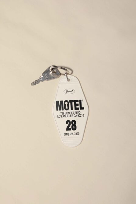Cream colored vintage motel key tag with black text, metal key attached