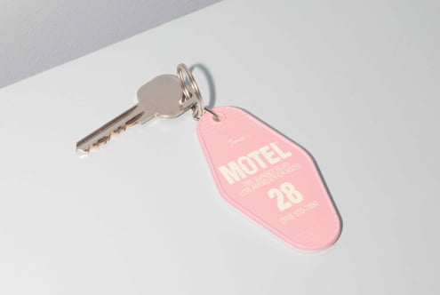 Pink motel key tag and silver key on white surface, perfect for mockup, vintage design, retro graphics, branding template, designer resource.