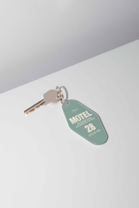 Vintage motel key mockup featuring a single key attached to a green key tag with motel information. Ideal for design projects and templates.