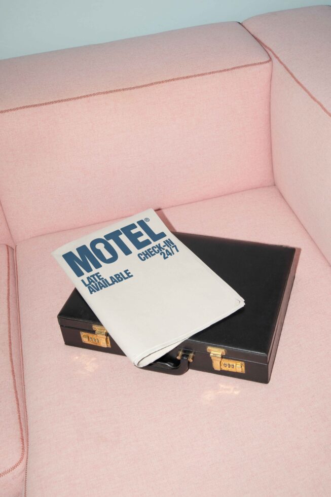 Motel brochure and black briefcase on pink sofa top view modern design elements template for mockups branding or presentation designers creative assets.