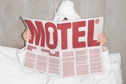Person in robe reading large print newspaper with Motel headline. Ideal for mockup design showcasing editorial layout, typography, and visual balance.