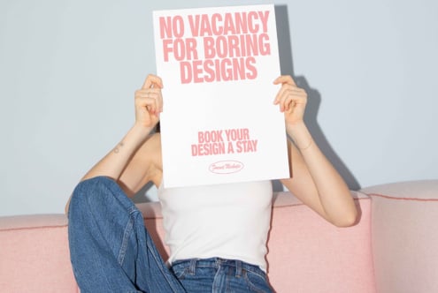Person holding a poster with No Vacancy for Boring Designs text. Creative template mockup for designers. Pink and white color scheme. Design resources.
