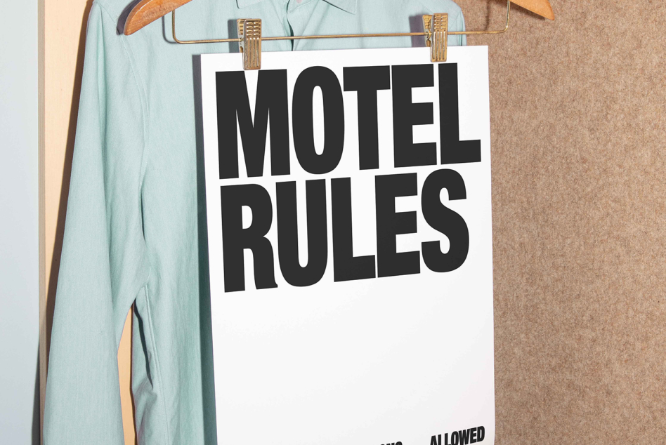 Motel Rules sign clipped to brass rail with light blue shirt hanging behind