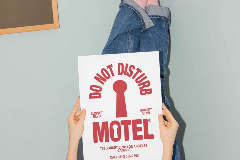 Person holding retro motel door hanger sign in red with keyhole graphic