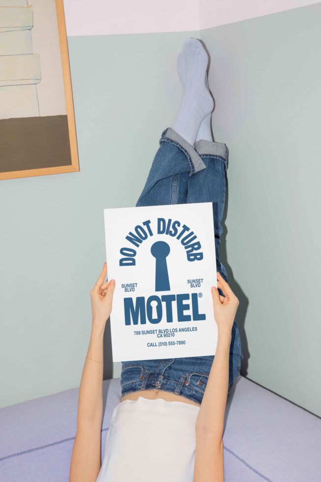 Person holding Motel sign mockup with Do Not Disturb text while lying on couch wearing jeans and socks minimal design scene for template use