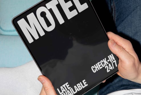 Tablet screen showcases a bold motel-themed graphic design with large white font. Perfect for mockups and template inspiration for designers.