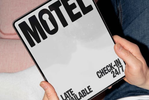 Person holds a tablet with bold black Motel sign and check-in details. Ideal for mockup design, graphics templates, typography, digital assets.