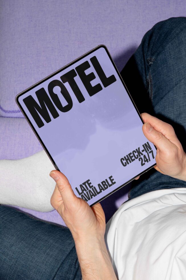 Person holding a digital tablet displaying a motel sign with bold black letters on a lavender background. Perfect for mockup showcasing fonts templates.