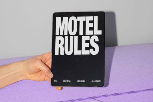 Hand holding tablet with bold text Motel Rules for digital design mockups. Perfect asset for designers needing unique typography graphics and templates.