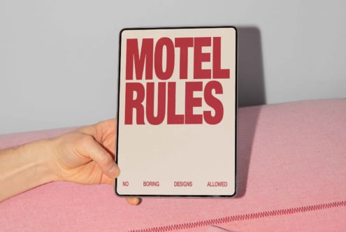 Hand holding a tablet with bold text reading Motel Rules against pink fabric backdrop. Perfect for design mockups, templates, graphics, digital assets.