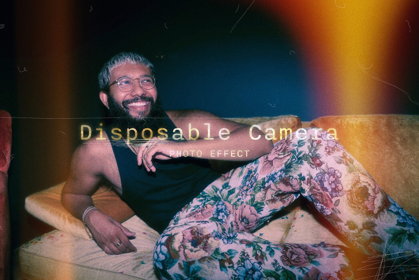 Vintage photo effect mockup with a man lounging on a couch wearing floral pants and glasses. Keywords: vintage mockup, disposable camera, photo effect.