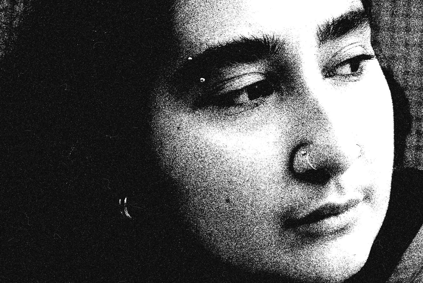 Grainy black and white portrait of a person with nose and eyebrow piercings, suitable for graphic design, texture overlay, or art prints in design projects.